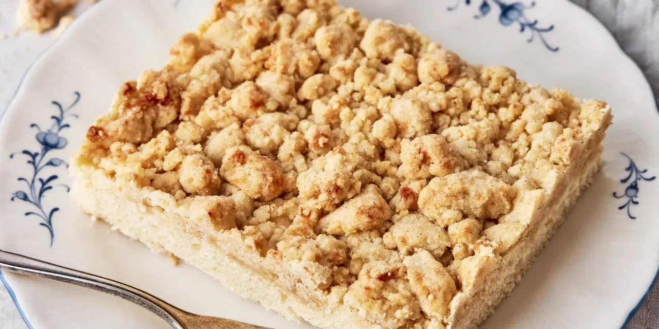 Ein Stück Streuselkuchen auf einem Teller mit Gabel. Dieses einfache Streuselkuchen Rezept gelingt immer!