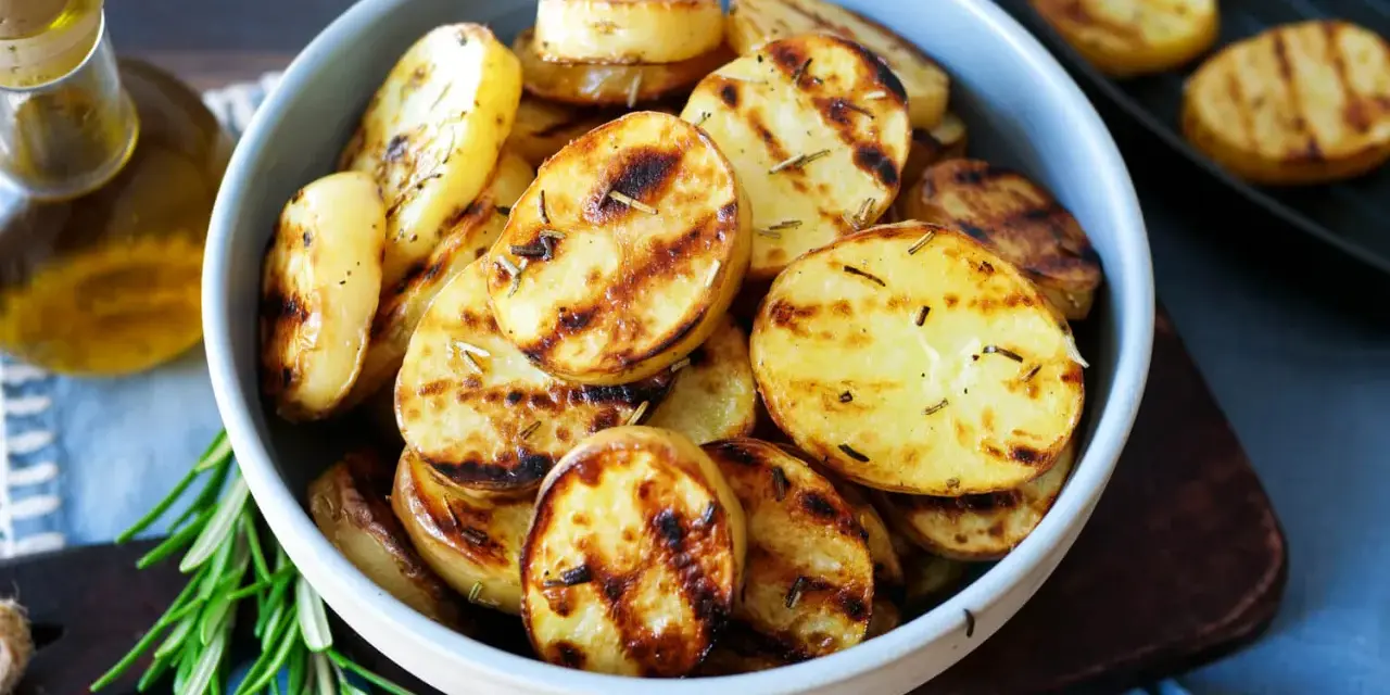 Schmackhafte Kartoffelscheiben mit Rosmarin, perfekt gegrillt. Die Streifen vom Grill sind deutlich sichtbar.