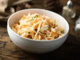 Schüssel mit cremigem Rettichsalat mit Apfel und Kräutern, serviert auf einem rustikalen Holztisch.