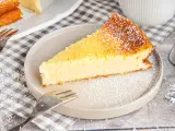 Ein saftiges Stück Kokoskuchen mit Pudding, gebacken in einer Springform, bestäubt mit Puderzucker.