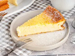 Ein saftiges Stück Kokoskuchen mit Pudding, gebacken in einer Springform, bestäubt mit Puderzucker.