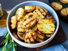 Schmackhafte Kartoffelscheiben mit Rosmarin, perfekt gegrillt. Die Streifen vom Grill sind deutlich sichtbar.