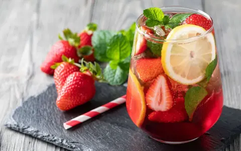 Erfrischende alkoholfreie Bowle mit Erdbeeren, Zitrone und Minze, serviert in einem Glas mit Eiswürfeln.