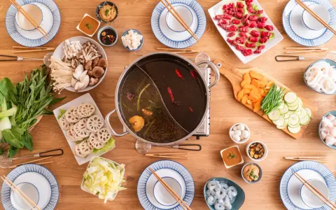 Zutaten für ein köstliches Hot Pot selber machen: Fleisch, Pilze, Gemüse, Garnelen und verschiedene Dips auf einem Holztisch arrangiert.