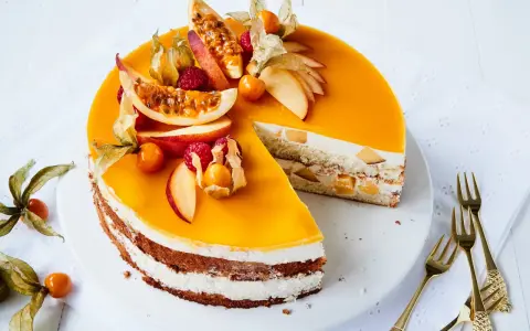 Eine köstliche Pfirsich Maracuja Torte mit frischen Früchten und Sahne. Ein Stück ist bereits angeschnitten.