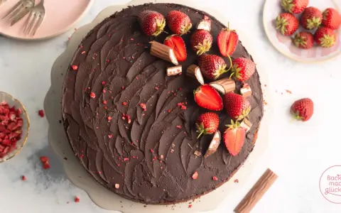 Eine köstliche Erdbeer Yogurette Torte mit Schokoladenglasur, frischen Erdbeeren und kleinen Schokostückchen.