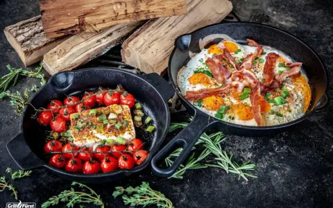 Zwei Gusseisenpfannen mit Eiern, Speck und Kirschtomaten mit Feta – perfekt für low carb grillen.
