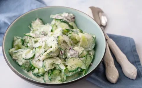 Frischer gurkensalat mit saurer sahne, Dill und roten Zwiebeln in einer Schüssel, bereit zum Servieren.