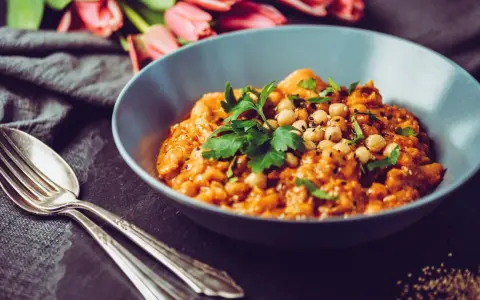 Herzhaftes Gericht mit Kichererbsen und Petersilie, verfeinert mit Garam Masala. Daneben liegen Gabel und Löffel.