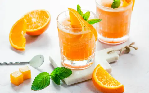 Erfrischender Aperol mit Orangensaft, garniert mit frischer Minze und Orangenspalten. Perfekt für einen sonnigen Nachmittag.