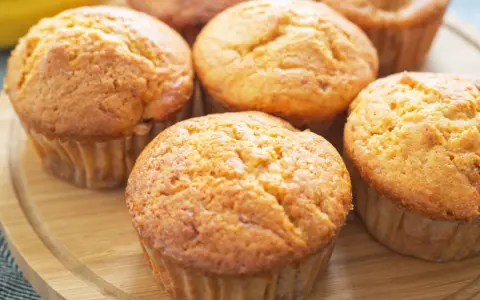 Goldbraune Bananen Quark Muffins auf einem Holzbrett, bereit zum Genießen.