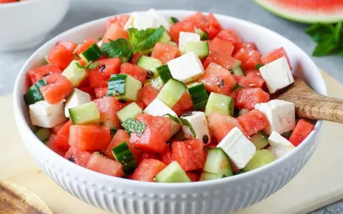 Erfrischender Wassermelone Feta Salat mit Gurke und Minze in einer weißen Schüssel, bereit zum Servieren.