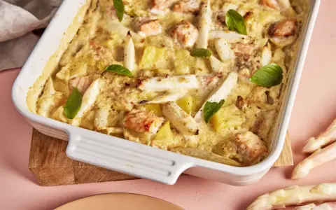 Ein köstlicher Spargel Lachs Auflauf in einer weißen Auflaufform, garniert mit Basilikum. Dazu frischer Spargel.