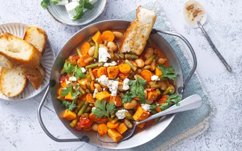 Herzhaftes Gericht mit Bohnen, Karotten und Süßkartoffeln, perfekt für Camping-Rezepte mit wenig Zutaten. Mit Feta und Brot serviert.