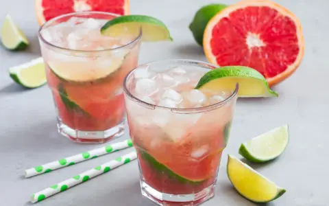 Erfrischender Aperol Paloma mit Grapefruit und Limette, garniert mit frischen Fruchtstücken und Eis.
