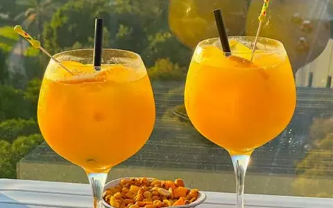 Zwei Gläser erfrischendes Aqua de Valencia mit Orangenscheiben und Eis, daneben eine Schale Nüsse.
