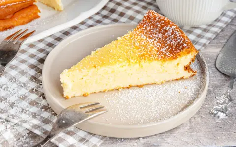 Ein saftiges Stück Kokoskuchen mit Pudding, gebacken in einer Springform, bestäubt mit Puderzucker.