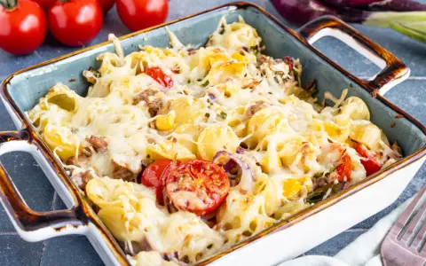 Herzhafter Nudel Thunfisch Auflauf mit geschmolzenem Käse, Tomaten und Zwiebeln, bereit zum Servieren.