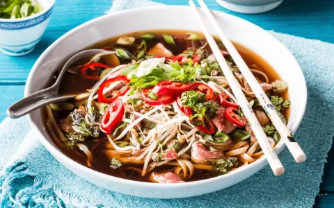 Eine Schüssel dampfendes Pho mit Rindfleisch, Nudeln, Sprossen und Chili. Was ist Pho? Ein aromatisches vietnamesisches Gericht.