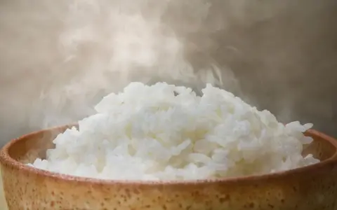 Dampfender Reis in einer Schale. Ein Beweis, dass Reis gesund ist und eine nahrhafte Mahlzeit darstellt.