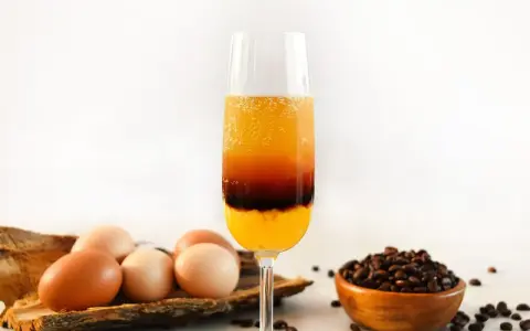 Schicht-Cocktail mit Ei, Kaffee und Orangensaft. Daneben liegen Eier und Kaffeebohnen.
