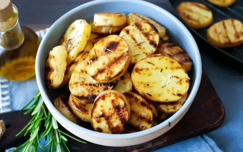 Schmackhafte Kartoffelscheiben mit Rosmarin, perfekt gegrillt. Die Streifen vom Grill sind deutlich sichtbar.