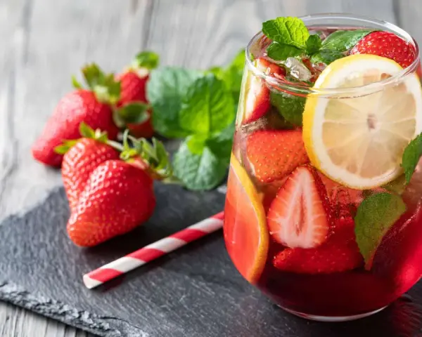 Erfrischende alkoholfreie Bowle mit Erdbeeren, Zitrone und Minze, serviert in einem Glas mit Eiswürfeln.