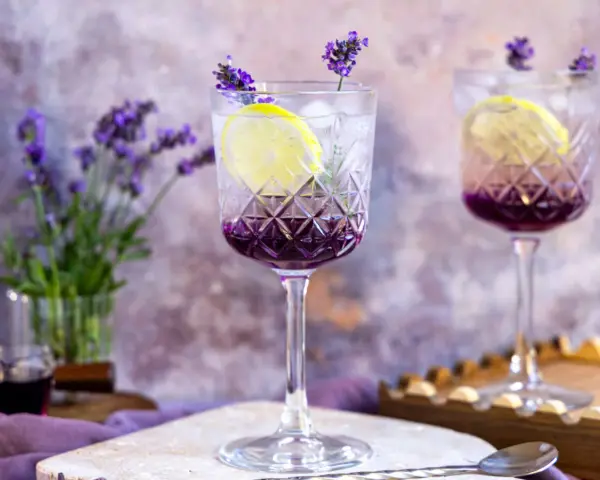 Erfrischender Lavendel Spritz mit Zitrone und Eis in eleganten Gläsern, garniert mit Lavendelblüten.