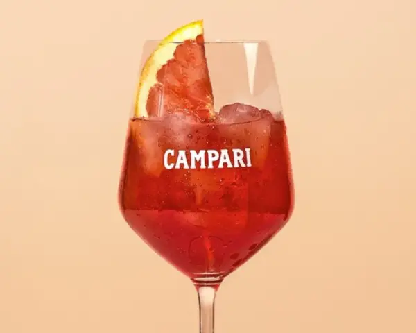 Ein Glas Campari mit Eis und einer Orangenscheibe. Entdecke die Vielfalt der Aperol Spritz Varianten!