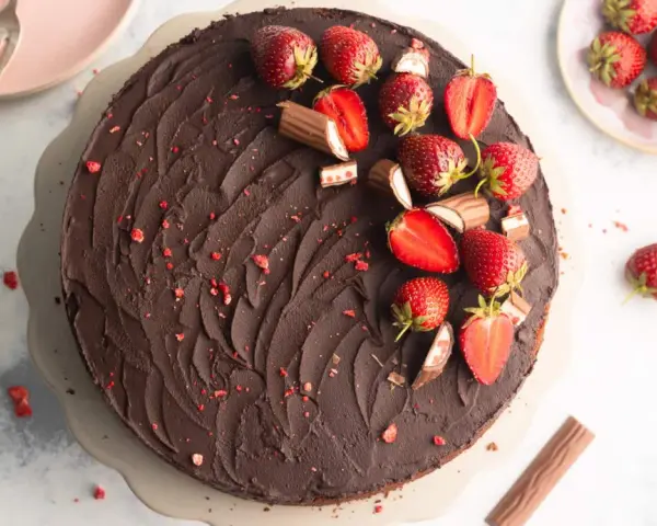Eine köstliche Erdbeer Yogurette Torte mit Schokoladenglasur, frischen Erdbeeren und kleinen Schokostückchen.
