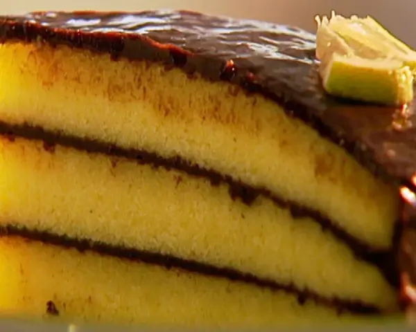 Ein saftiges Stück schoko zitronen kuchen mit Schokoladenglasur und einem Limettenschnitz.