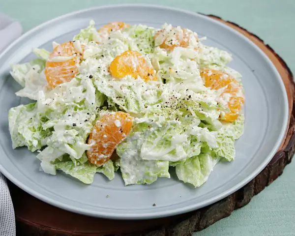 Frischer Chinakohlsalat mit saftigen Mandarinenstücken, cremig angemacht und mit Pfeffer bestreut. Ein leichter Genuss!