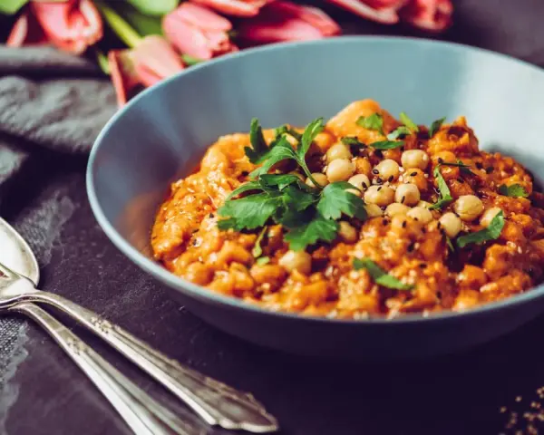 Herzhaftes Gericht mit Kichererbsen und Petersilie, verfeinert mit Garam Masala. Daneben liegen Gabel und Löffel.