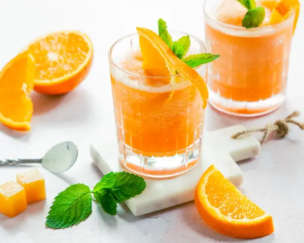 Erfrischender Aperol mit Orangensaft, garniert mit frischer Minze und Orangenspalten. Perfekt für einen sonnigen Nachmittag.