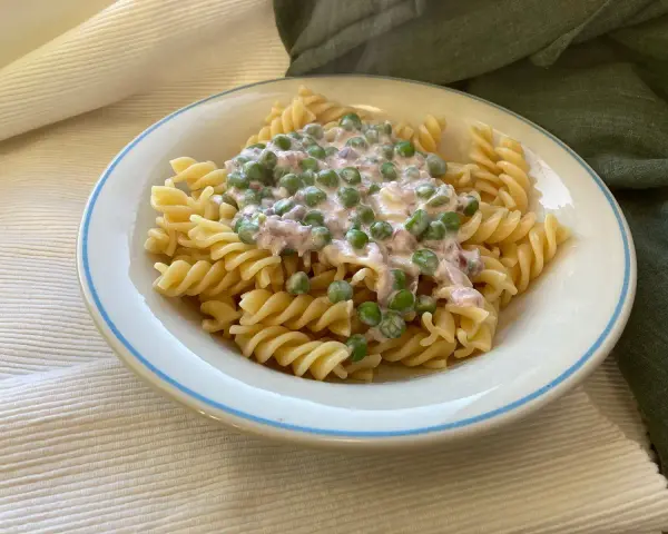 Fusilli-Pasta mit einer cremigen Sauce aus Erbsen und Speck, ein klassisches italienisches Gericht.