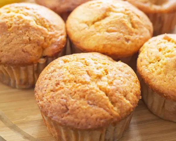 Goldbraune Bananen Quark Muffins auf einem Holzbrett, bereit zum Genießen.