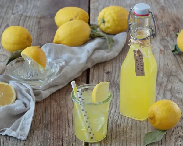 Frische Zitronen und selbstgemachter Zitronensirup in einer Flasche, bereit zum Genießen.