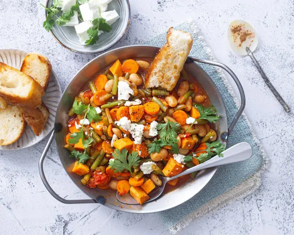 Herzhaftes Gericht mit Bohnen, Karotten und Süßkartoffeln, perfekt für Camping-Rezepte mit wenig Zutaten. Mit Feta und Brot serviert.