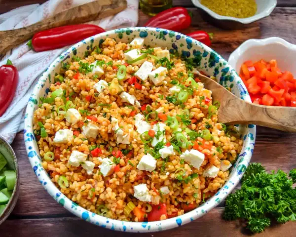 Frischer bulgursalat mit feta, Tomaten, Paprika und Frühlingszwiebeln, garniert mit Petersilie.