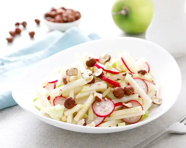 Frischer Kohlrabi-Apfel-Salat mit Radieschen und Haselnüssen, ein leichter Genuss.