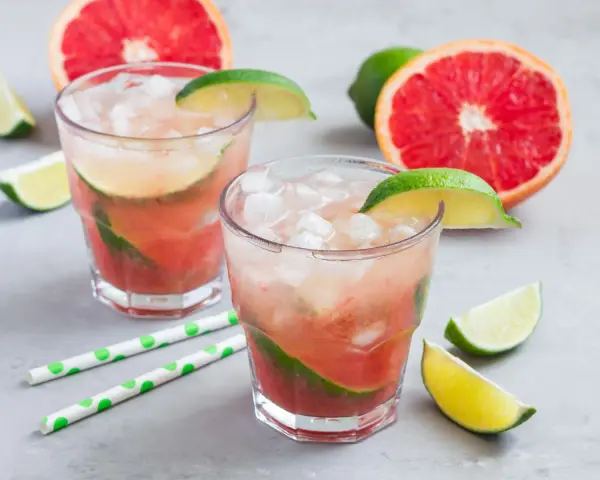 Erfrischender Aperol Paloma mit Grapefruit und Limette, garniert mit frischen Fruchtstücken und Eis.