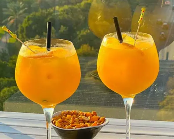 Zwei Gläser erfrischendes Aqua de Valencia mit Orangenscheiben und Eis, daneben eine Schale Nüsse.