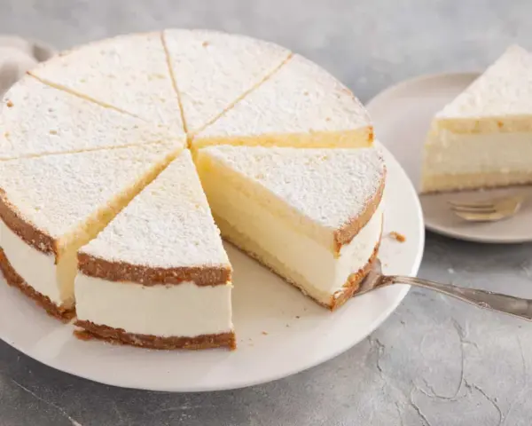 Leichter Biskuitkuchen mit cremiger Füllung, bestäubt mit Puderzucker. Neue Kuchen Rezepte zum Nachbacken.