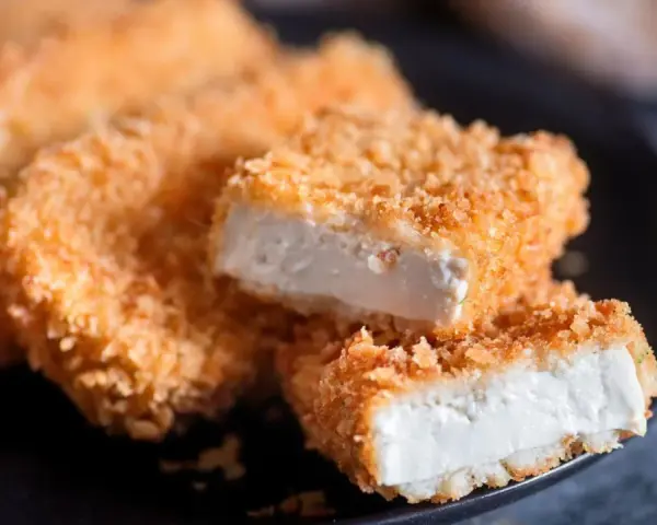 Knusprig gebratenes Tofu auf einem Teller. Die goldbraune Panade umhüllt das weiche Innere. Perfekt, um Tofu knusprig braten zu lernen.