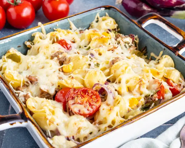 Herzhafter Nudel Thunfisch Auflauf mit geschmolzenem Käse, Tomaten und Zwiebeln, bereit zum Servieren.