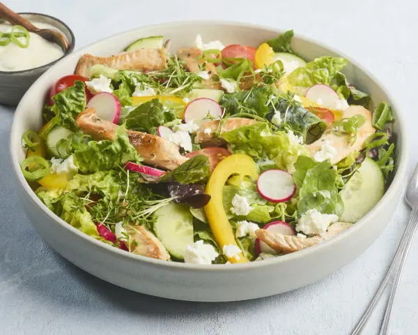 Frischer Salat mit Putenstreifen, Gurken, Radieschen, Tomaten, gelber Paprika und Feta. Dazu ein cremiges Dressing.