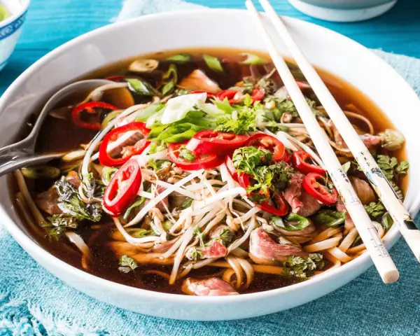 Eine Schüssel dampfendes Pho mit Rindfleisch, Nudeln, Sprossen und Chili. Was ist Pho? Ein aromatisches vietnamesisches Gericht.