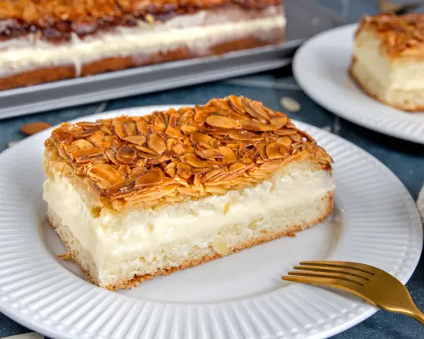 Ein Stück Bienenstich ohne Hefe mit cremiger Füllung und karamellisierten Mandeln. Ein köstliches Rezept für jeden Anlass.