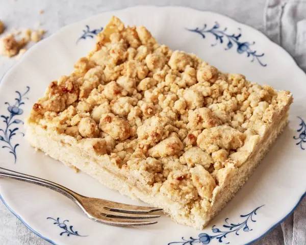 Ein Stück Streuselkuchen auf einem Teller mit Gabel. Dieses einfache Streuselkuchen Rezept gelingt immer!