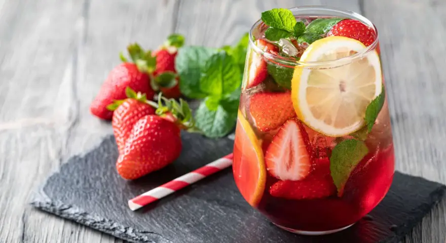 Erfrischende alkoholfreie Bowle mit Erdbeeren, Zitrone und Minze, serviert in einem Glas mit Eiswürfeln.